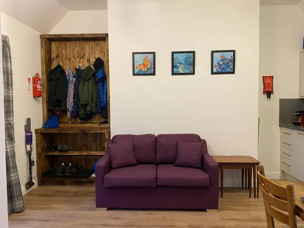 a living room with a purple couch and a table at Butterfly Cottage in Grantown on Spey