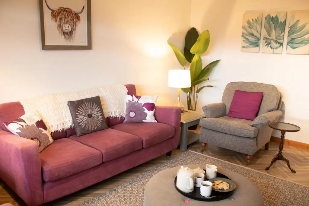 a living room with a couch and a chair at Burnside Pines in Aviemore
