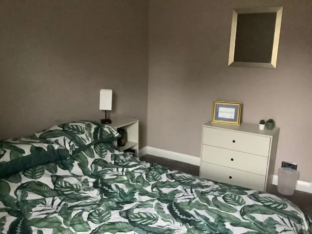 a bedroom with a green and white bed and a dresser at 4 Stills Apartment in Rothes
