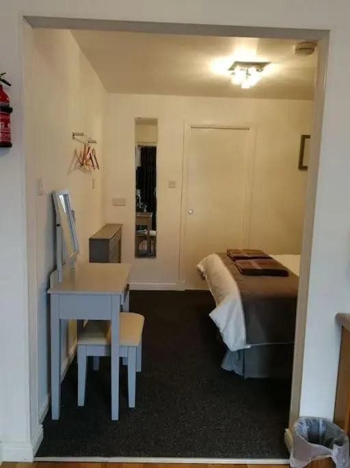 a bedroom with a bed and a desk and a table at Avalon Studio. Comfy well equipped cosy studio. in Aviemore