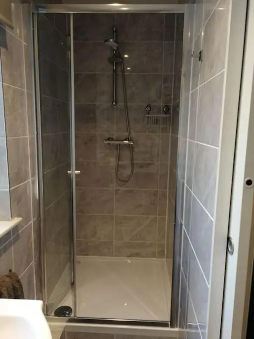 a shower with a glass door in a bathroom at Avalon Studio. Comfy well equipped cosy studio. in Aviemore