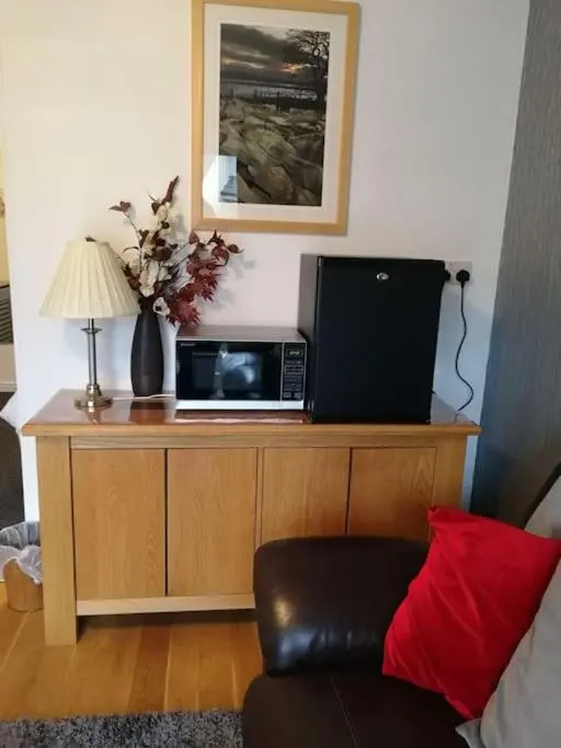a microwave sitting on top of a wooden cabinet at Avalon Studio. Comfy well equipped cosy studio. in Aviemore