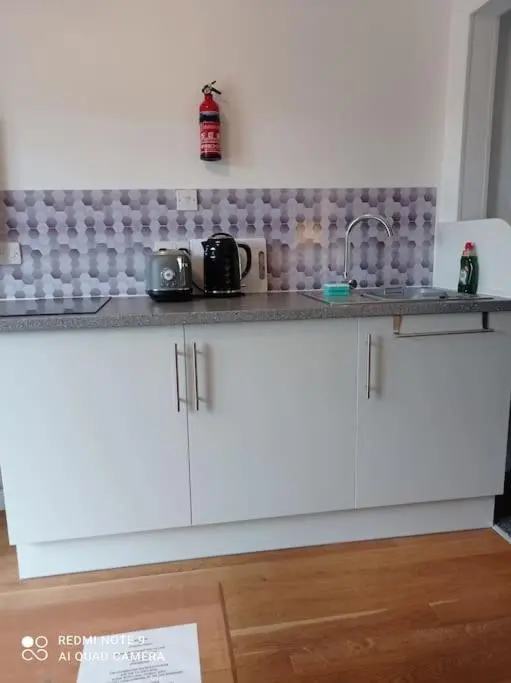 a kitchen with white cabinets and a sink at Avalon Studio. Comfy well equipped cosy studio. in Aviemore