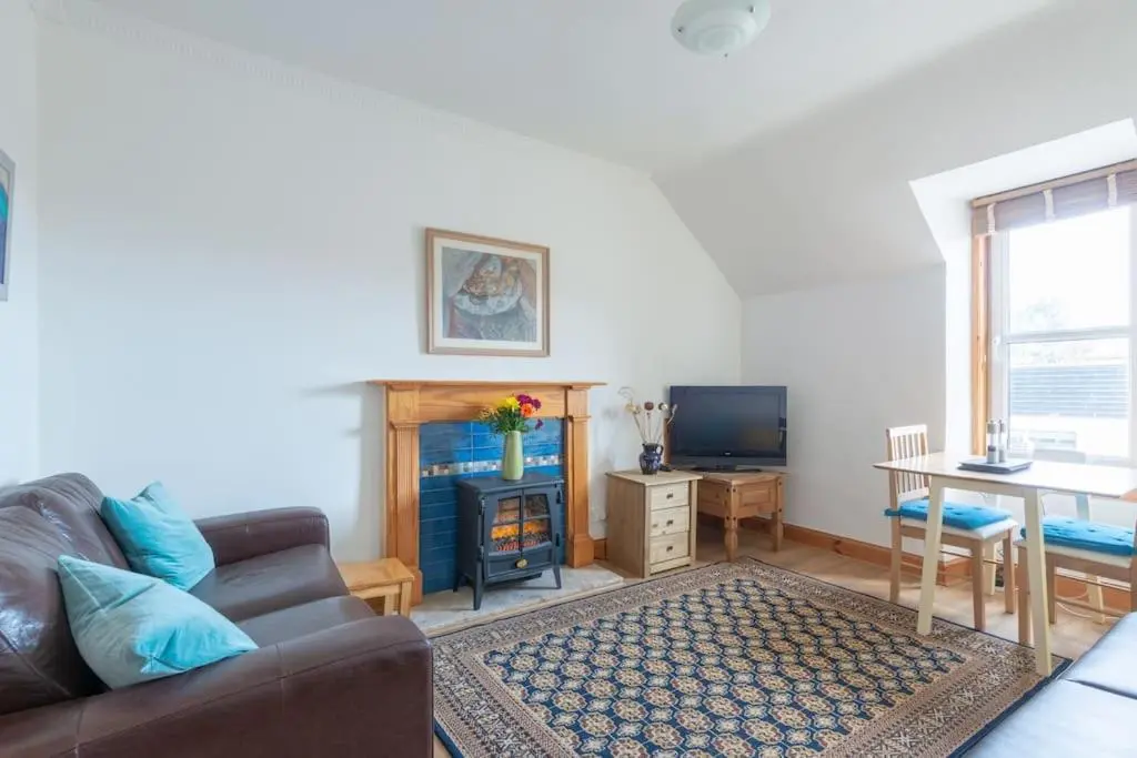 a living room with a couch and a table and a television at The 'Fairy Hill' Apartment in Inverness