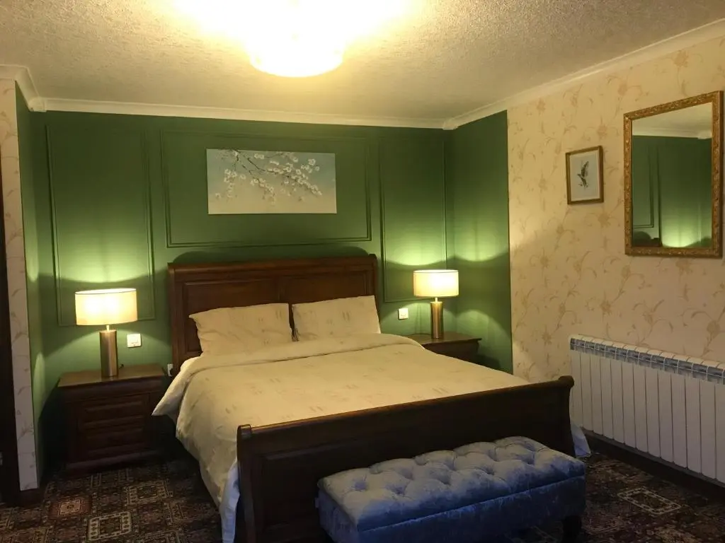 a bedroom with green walls and a bed and two lamps at Pine Chalet in Muir of Ord