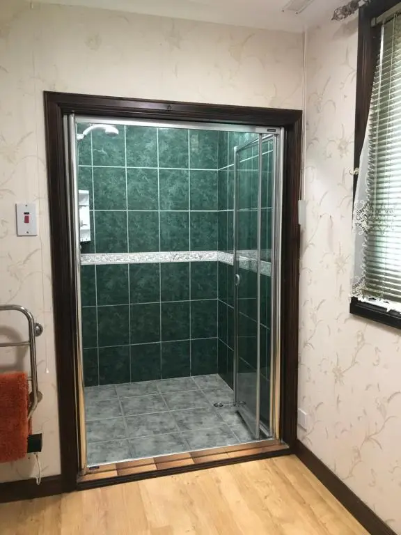 a shower with a glass door in a bathroom at Pine Chalet in Muir of Ord