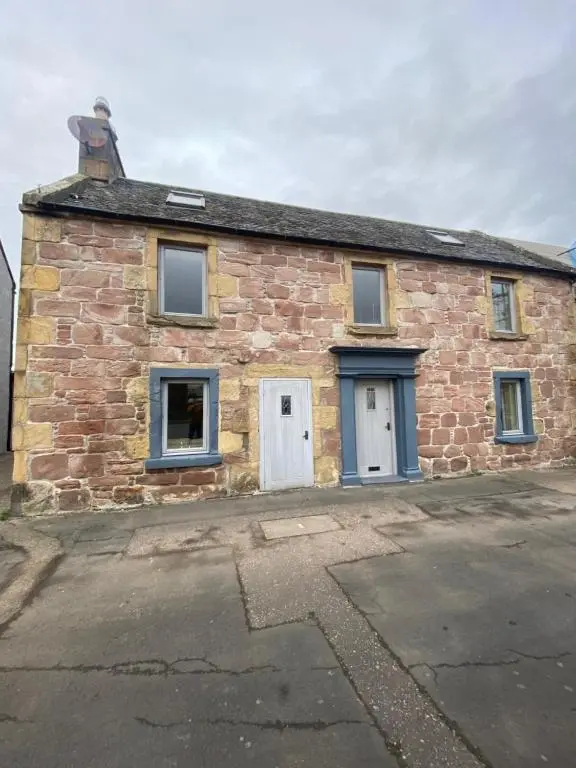an old brick building with two white doors at Little Ship Inn Rooms in Invergordon