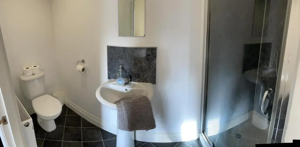 a bathroom with a shower and a sink and a toilet at Little Ship Inn Rooms in Invergordon