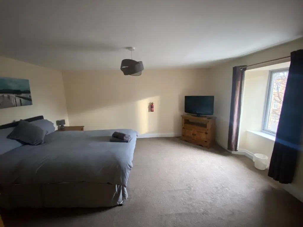 a bedroom with a bed and a tv and a window at Little Ship Inn Rooms in Invergordon