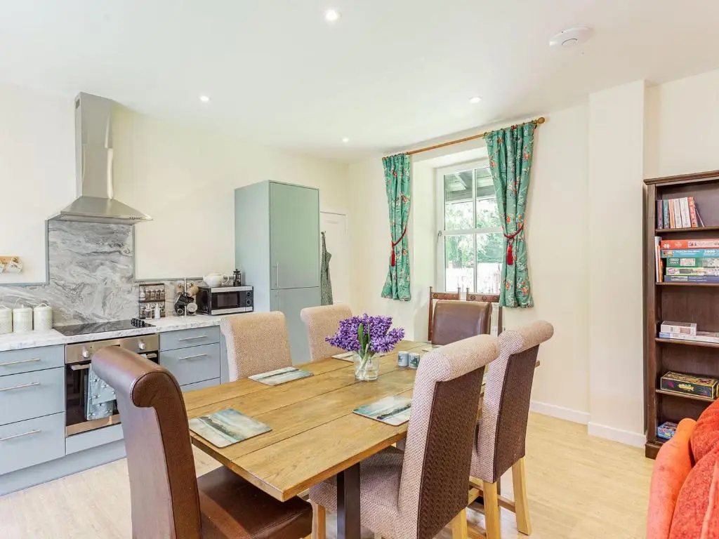 a kitchen and dining room with a wooden table and chairs at New Cottage in Farr