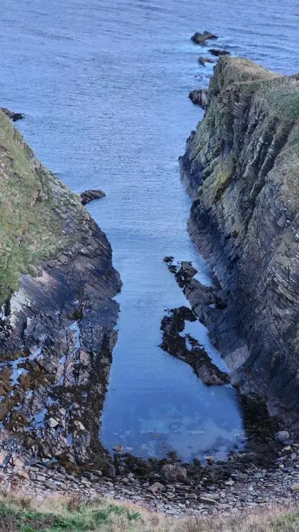 a body of water next to a rocky coastline at Castle Shieling in Latheron