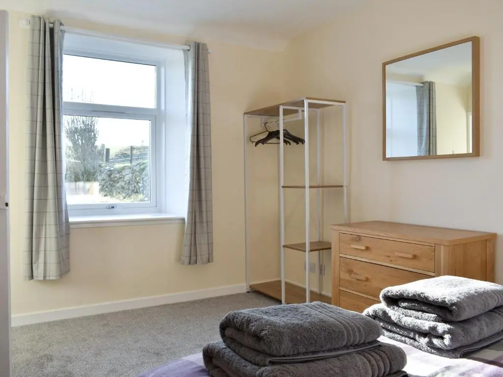 a bedroom with a mirror and a dresser and a window at Benwells Holiday Cottage in Maud