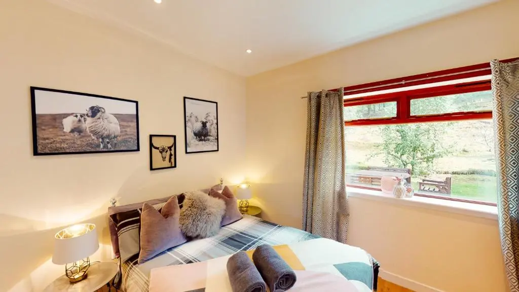 a bedroom with a bed and a window at Druim An Lochain Cottage in Kinrara