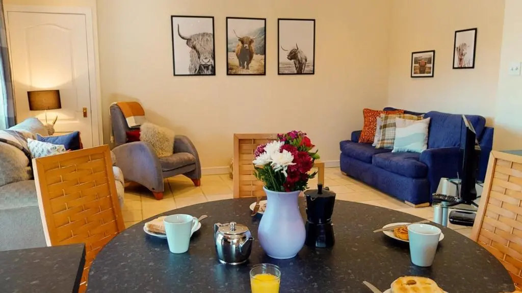 a living room with a table with a vase of flowers at Druim An Lochain Cottage in Kinrara