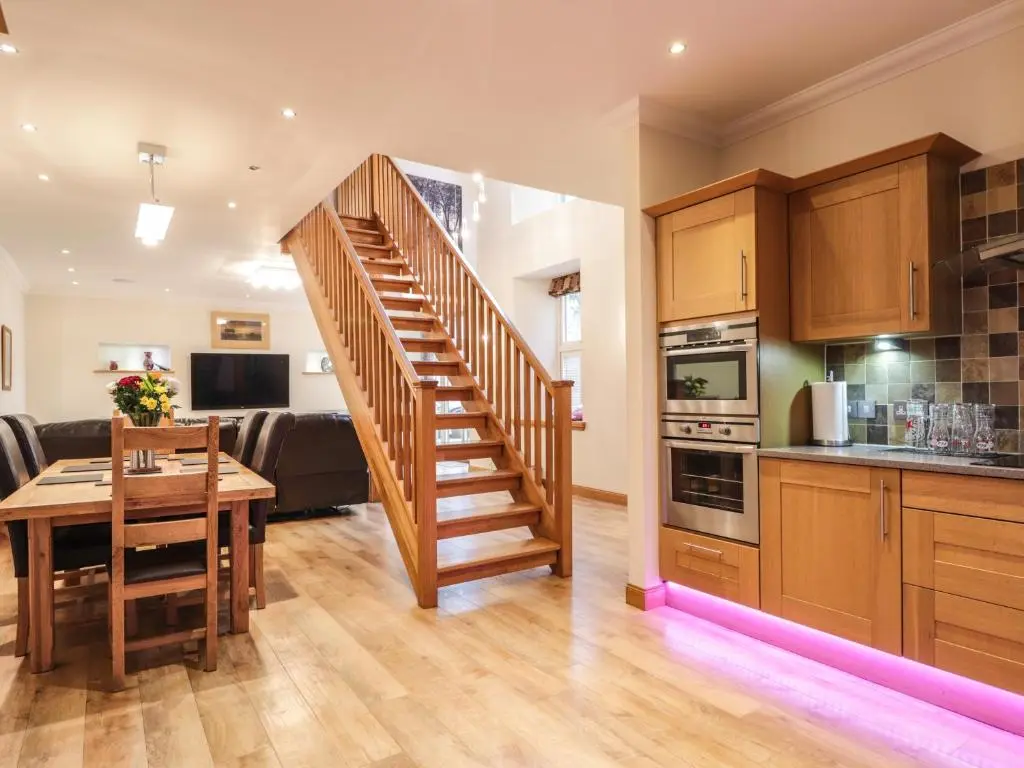 a kitchen with a wooden staircase leading to a dining room at 1 The Coach House in Elgin