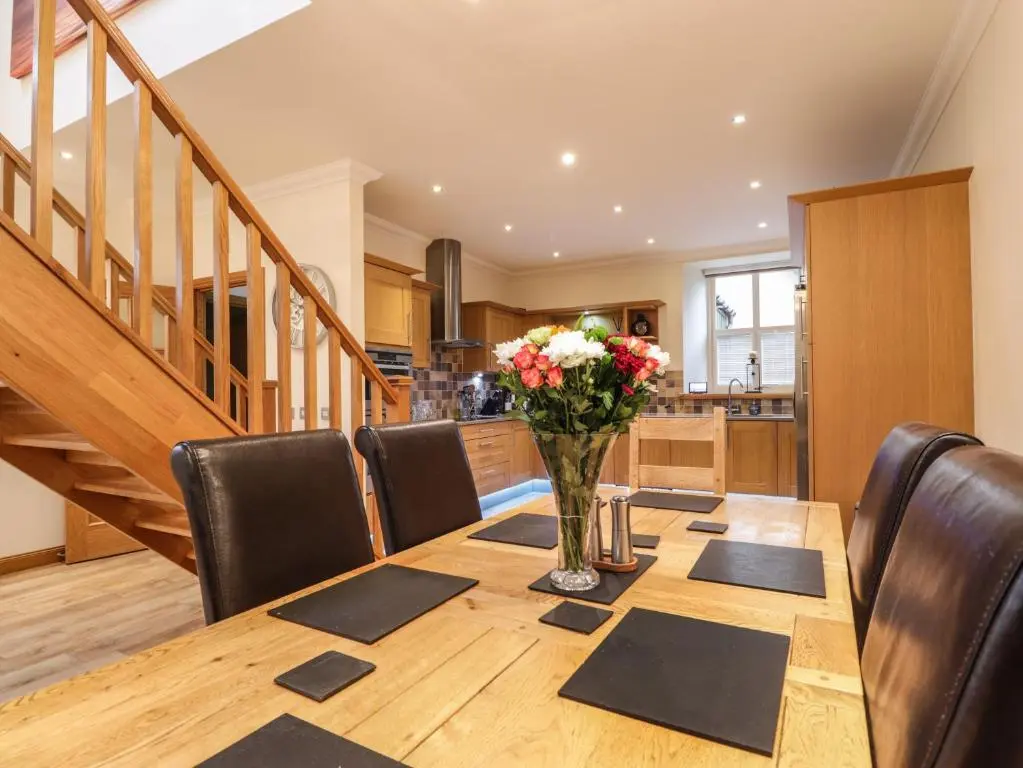 a dining room table with a vase of flowers on it at 1 The Coach House in Elgin