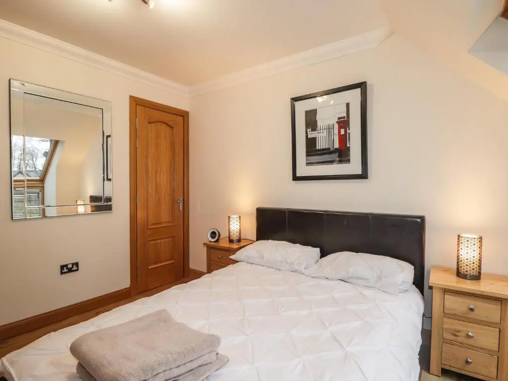 a bedroom with a large white bed and a mirror at 1 The Coach House in Elgin