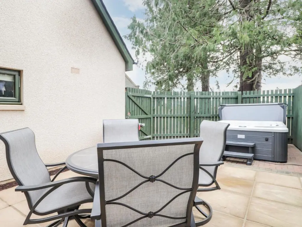 a patio with a table and chairs and a grill at 1 The Coach House in Elgin