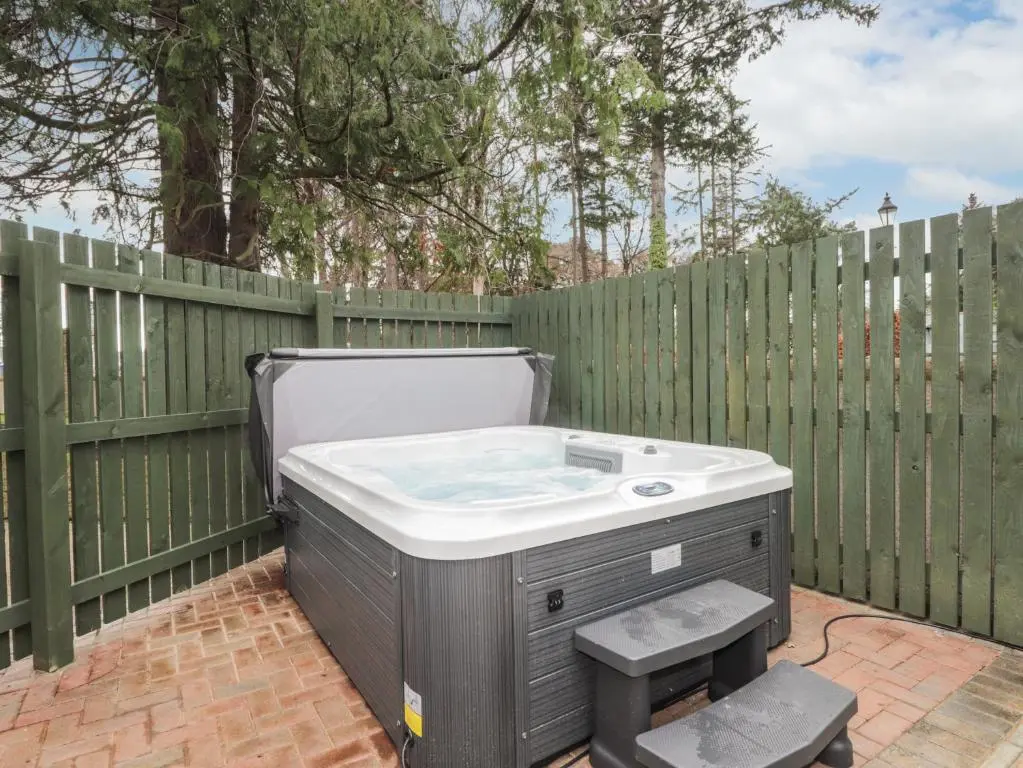 a hot tub sitting next to a wooden fence at 1 The Coach House in Elgin