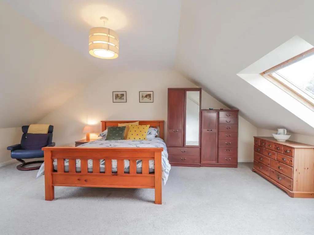 a bedroom with a bed and a chair in a attic at Iola in Inverness