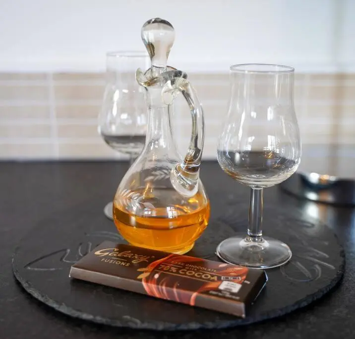 a bottle of whiskey and two glasses on a table at Wee Blondie's Ski Cottage in Aviemore