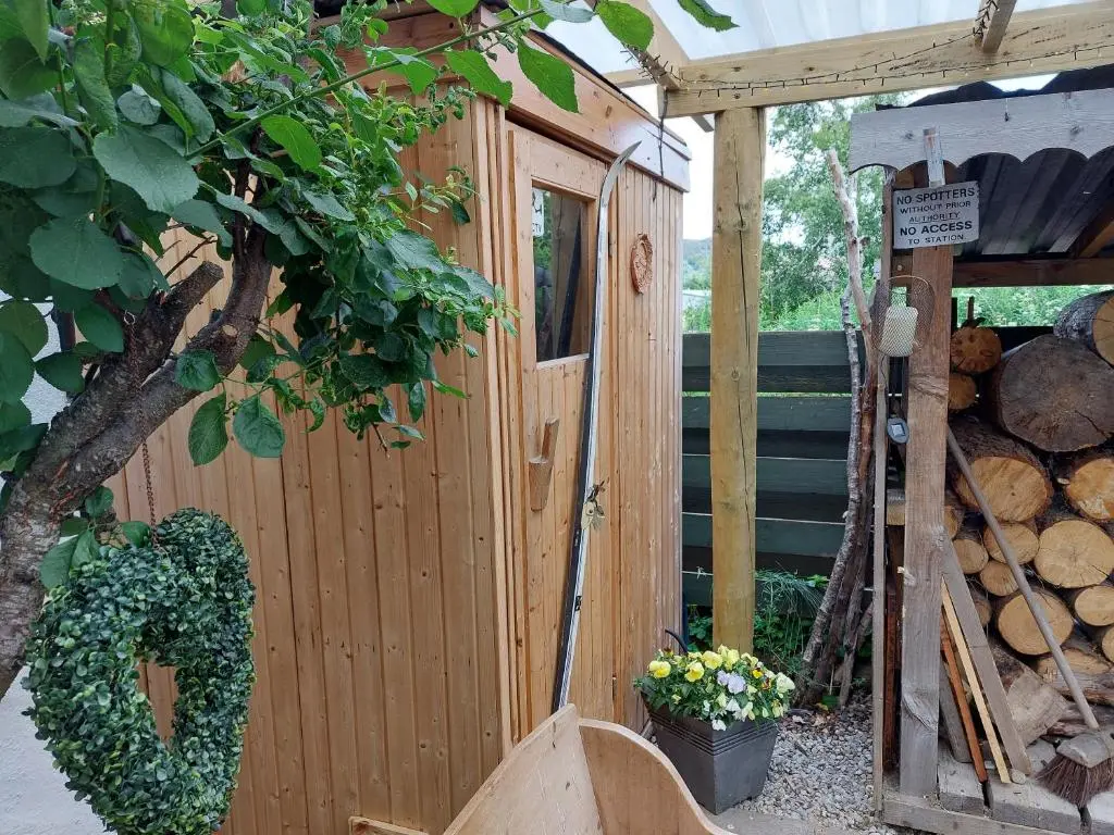 a wooden cabin with a fence and a tree at Wee Blondie's Ski Cottage in Aviemore