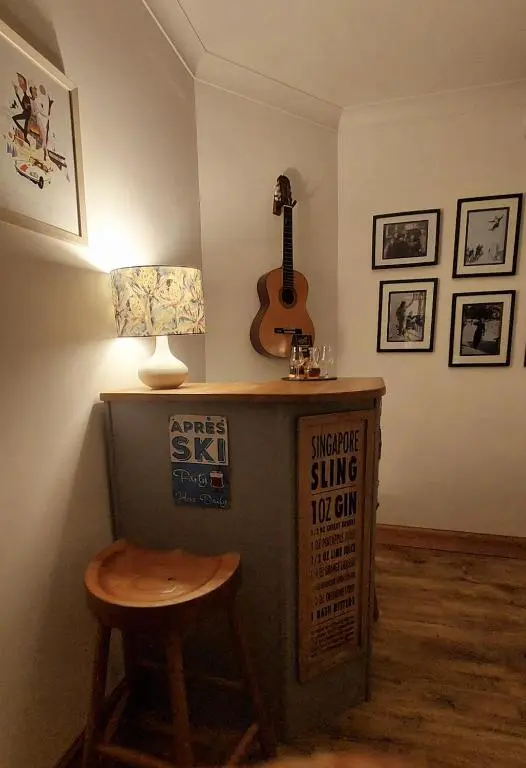 a room with a table with a guitar and a stool at Wee Blondie's Ski Cottage in Aviemore