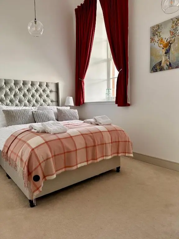 a bedroom with a bed with red curtains and a window at 38 Great Glen Townhouse Inverness in Inverness