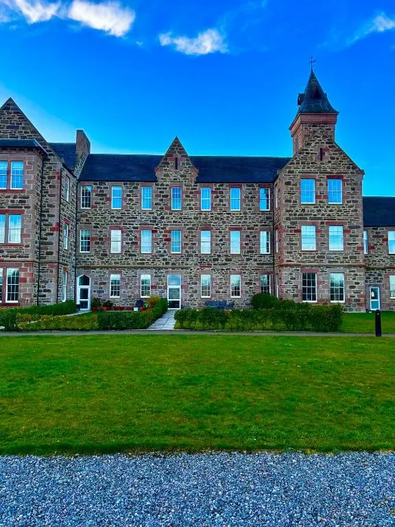 a large brick building with a grass field in front at 38 Great Glen Townhouse Inverness in Inverness