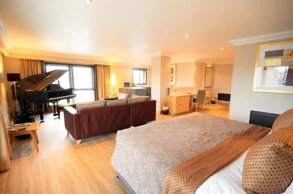 a bedroom with a bed and a living room with a piano at The Mansefield Hotel in Elgin