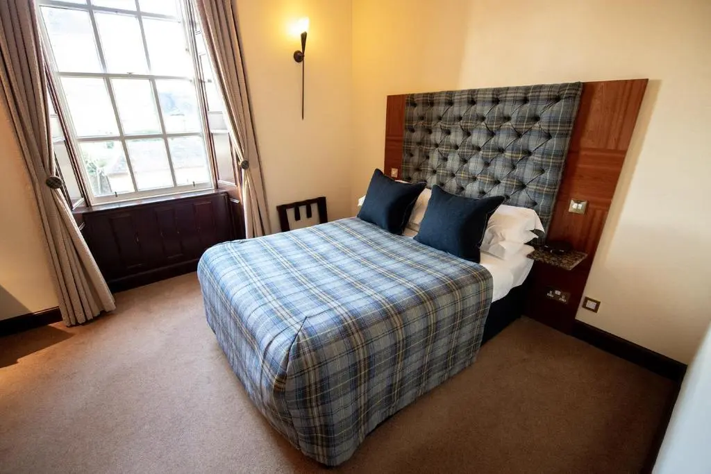 a bedroom with a bed with a plaid blanket at The Mansefield Hotel in Elgin