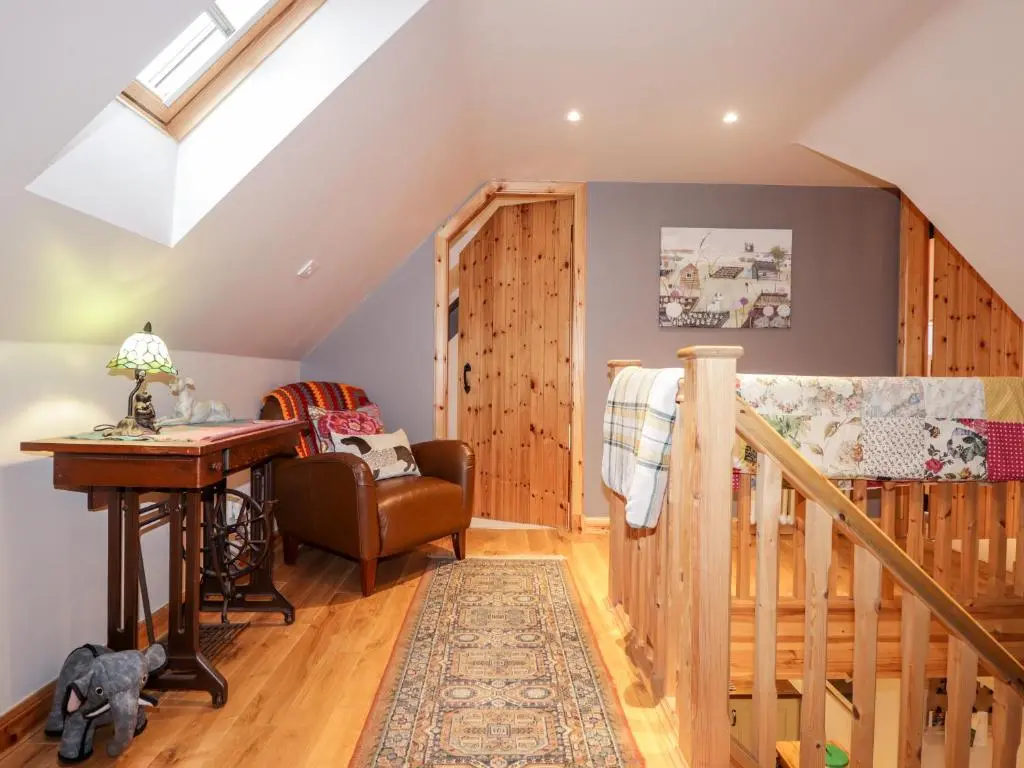 a room with a staircase and a desk and a table at Bogindour Cottage in Muir of Ord