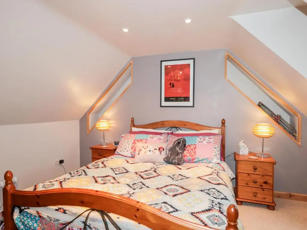 a bedroom with a bed and two lamps at Bogindour Cottage in Muir of Ord