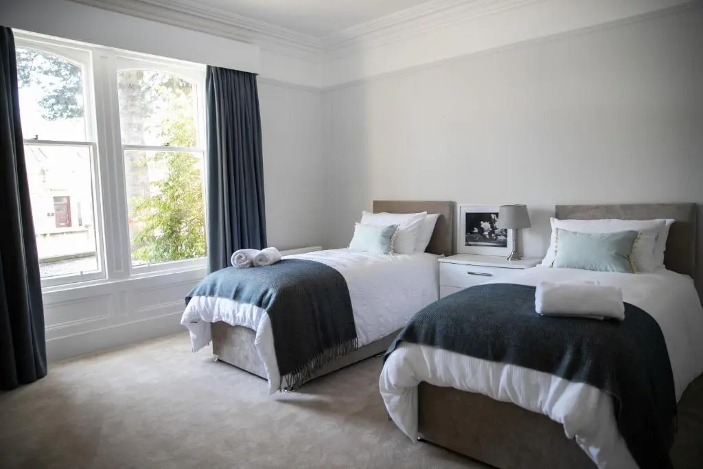 a white bedroom with two beds and a window at Whitecraigs in Elgin