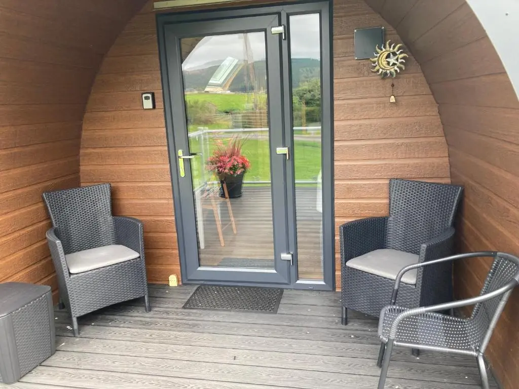 a patio with two chairs and a door with a plant at Robins Nest Glamping Pod with Hot Tub in Keith
