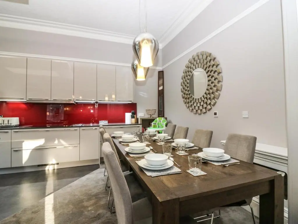 a dining room with a table and a kitchen at Mavisbank in Peterhead