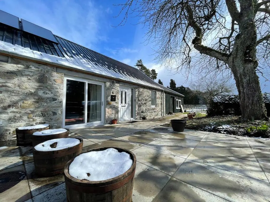 a stone cottage with two stools in front of it at Farr Out in Farr