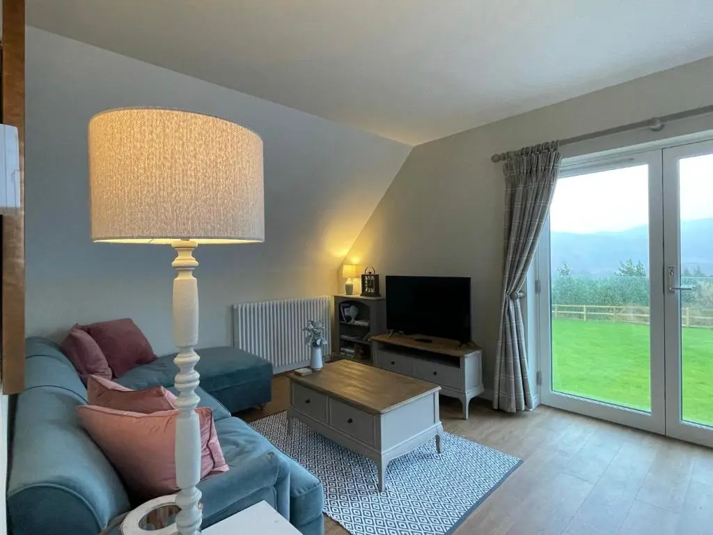 a living room with a blue couch and a lamp at Little Thistle Apartment in Whitebridge