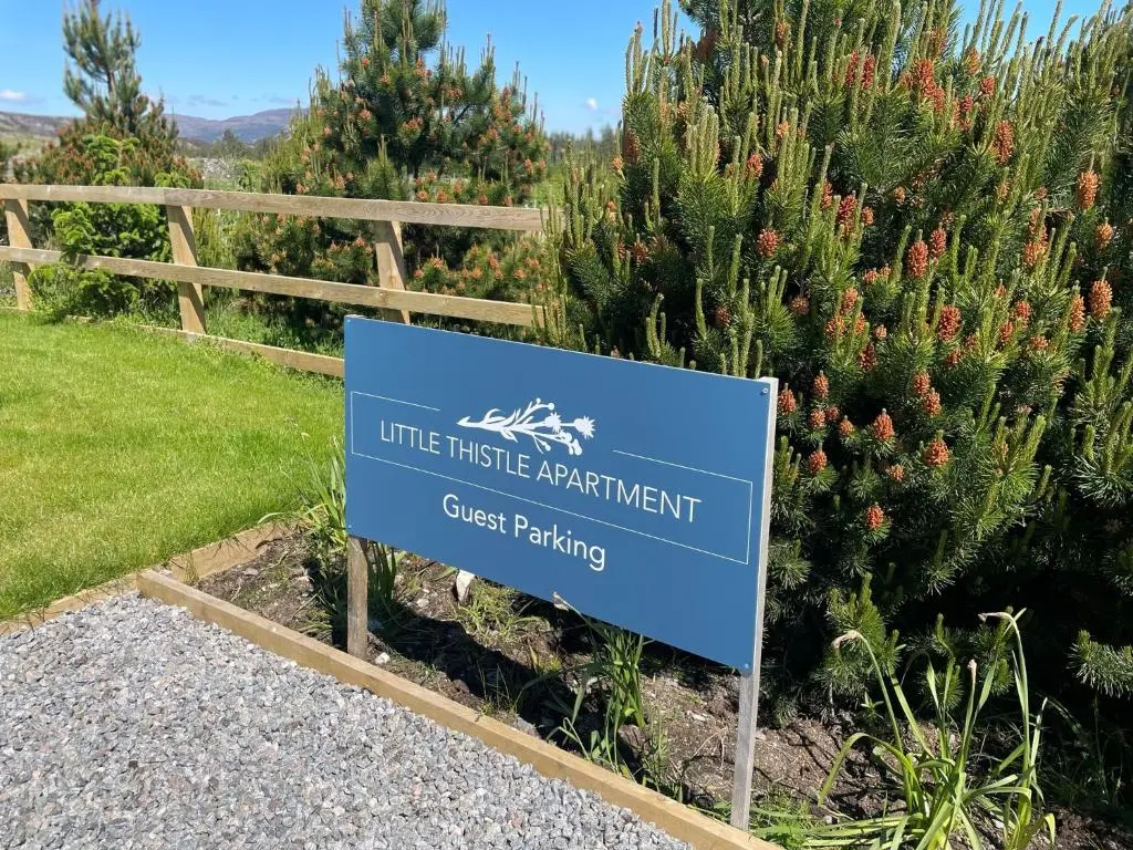 a blue sign in front of some bushes at Little Thistle Apartment in Whitebridge
