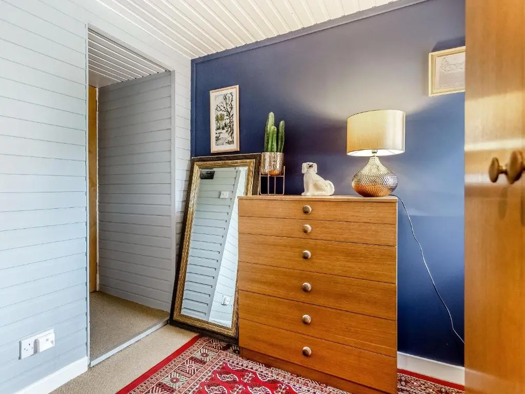 a bedroom with a dresser with a lamp on it at Holly Tree Cottage in Tain