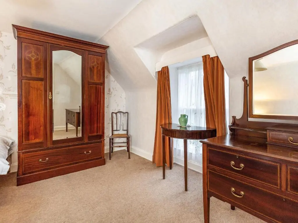 a bedroom with a dresser and a mirror at Isla Bank Cottage in Keith