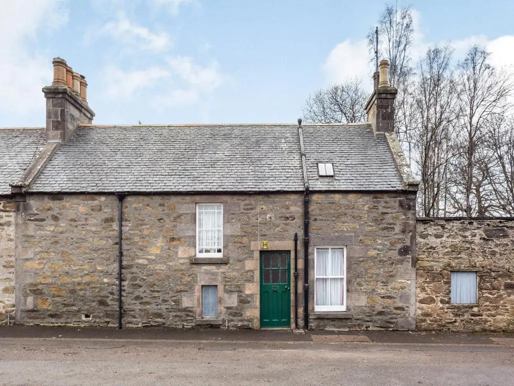 an old stone building with a green door at Isla Bank Cottage in Keith