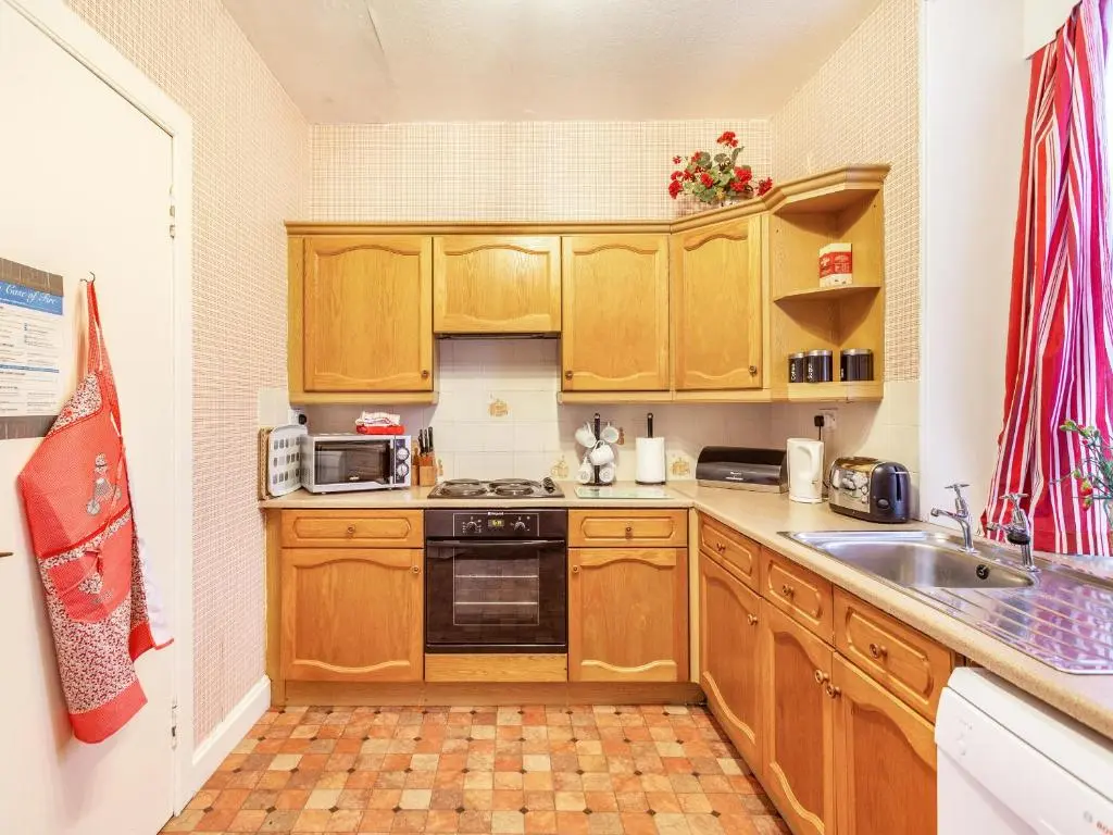 a small kitchen with wooden cabinets and a sink at Isla Bank Cottage in Keith
