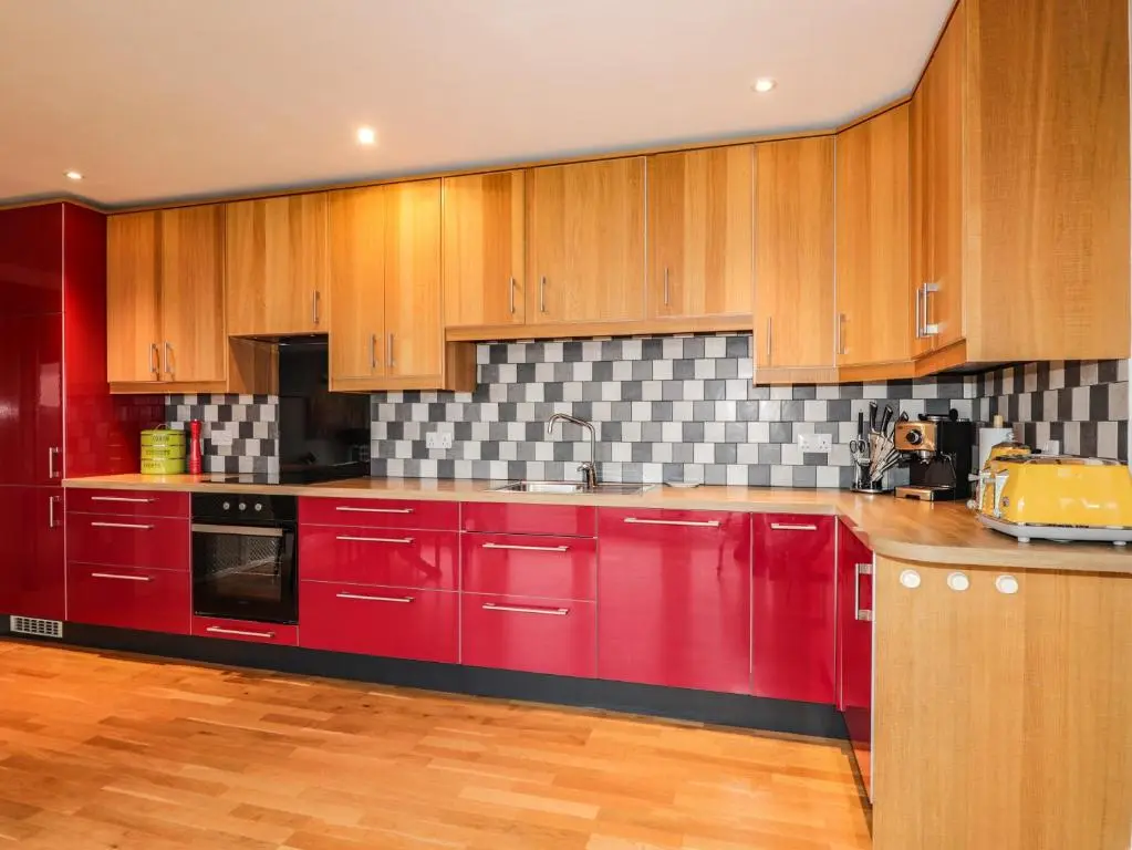 a red kitchen with wooden cabinets and a sink at Sealladh Mor in Rogart