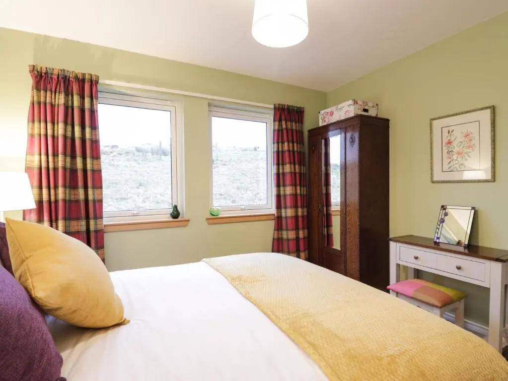 a bedroom with a bed and two windows at Sealladh Mor in Rogart