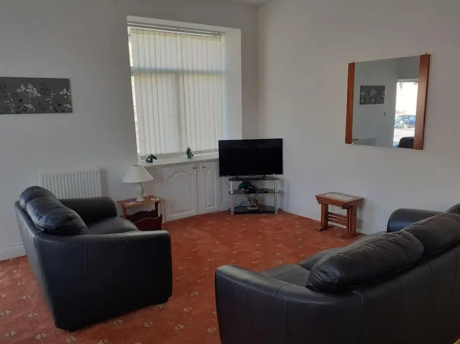 a living room with two couches and a flat screen tv at Lossiemouth Seaside Flat in Lossiemouth