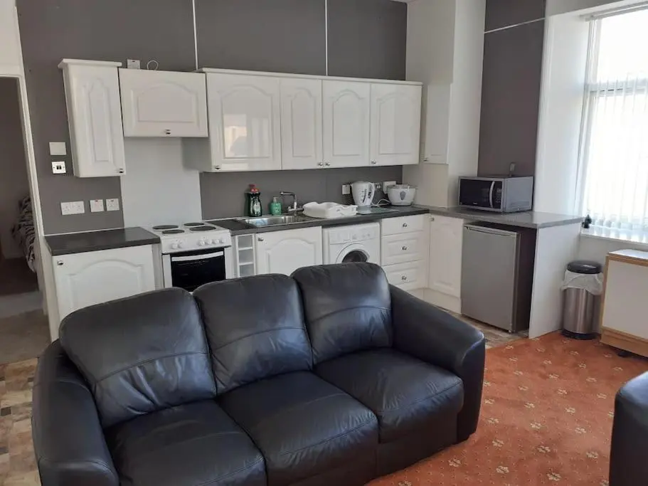 a living room with a couch in front of a kitchen at Lossiemouth Seaside Flat in Lossiemouth