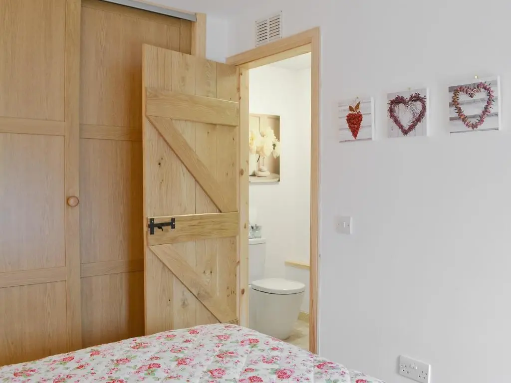 a bedroom with a sliding barn door and a toilet at Paterson Cottage in Tore