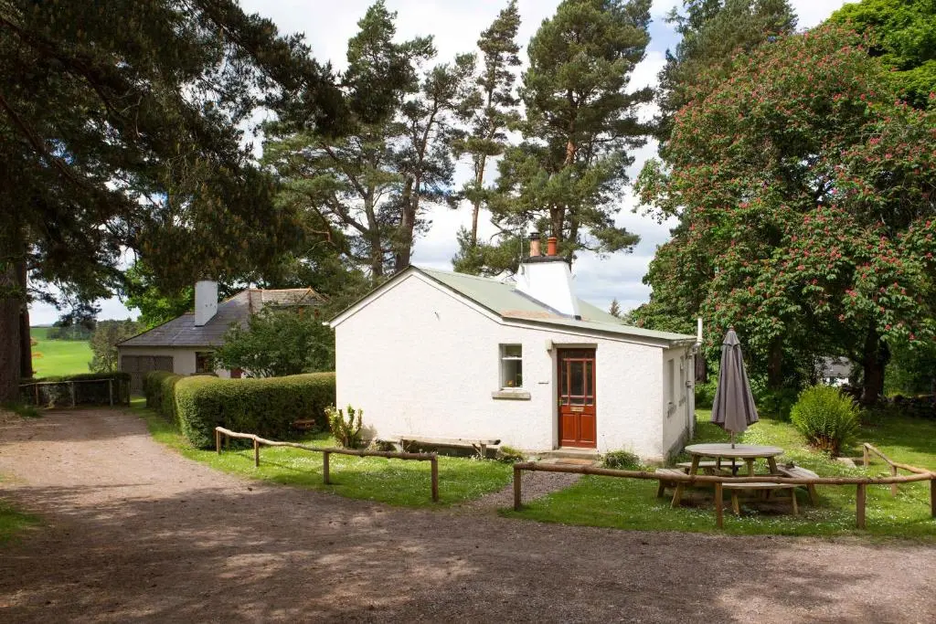 a small white house with a picnic table and a picnic table at The Bungalow in Elgin
