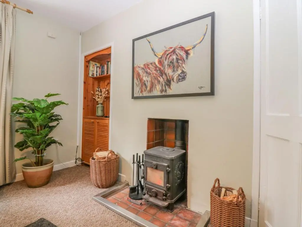 a living room with a fireplace and a picture of a cow at The Bungalow in Elgin